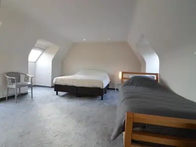 a bedroom with two beds and a chair at Splendid villa in Flemish Ardennes with pool in Wolvenhoek
