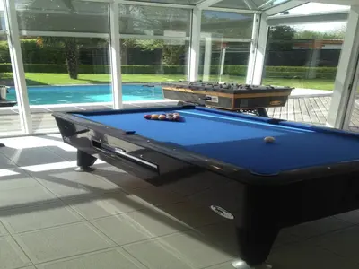 a pool table in a room next to a swimming pool at Splendid villa in Flemish Ardennes with pool in Wolvenhoek