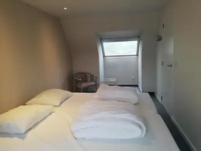 a bedroom with two beds with white sheets and a window at Splendid villa in Flemish Ardennes with pool in Wolvenhoek