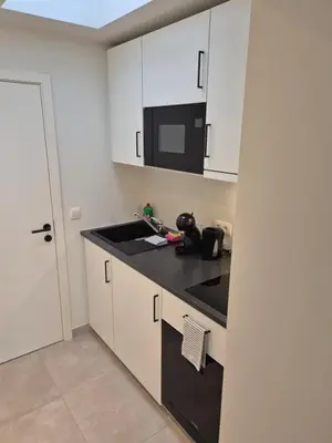 a kitchen with white cabinets and a black counter top at Huis ALNA 10 in Mechelen