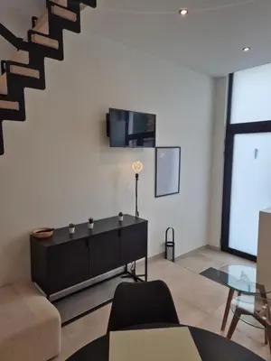 a living room with a couch and a tv on a wall at Huis ALNA 10 in Mechelen