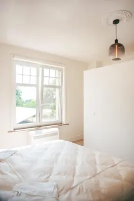 a white bedroom with a bed and a window at Villa Paulette