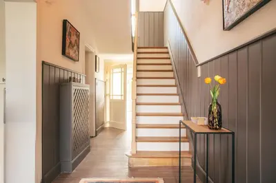 a hallway with stairs and a vase of flowers on a table at Villa Paulette