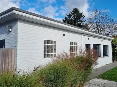a white building with windows in a yard at Le Jardin in Wommelgem