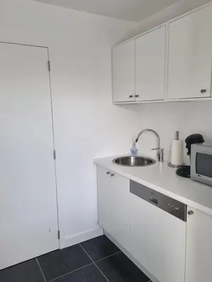 a white kitchen with a sink and a microwave at Le Jardin in Wommelgem
