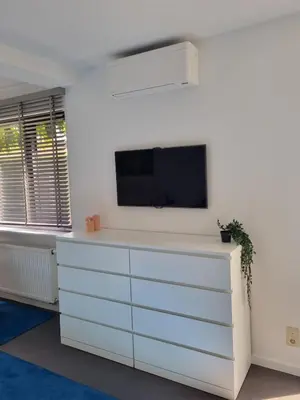 a living room with a white dresser with a tv on a wall at Le Jardin in Wommelgem