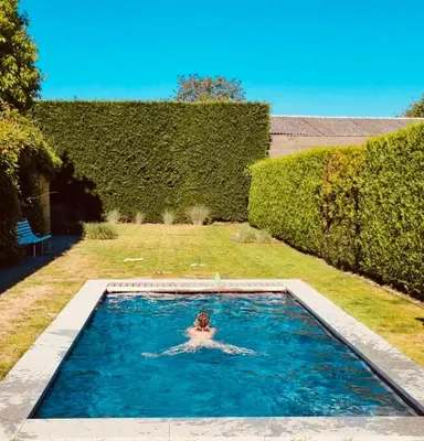 a person in a swimming pool in a yard at Le Jardin in Wommelgem
