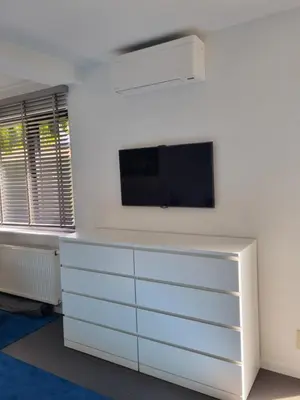 a white dresser with a tv on a wall at Le Jardin in Wommelgem