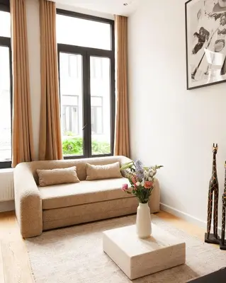 a living room with a couch and a vase of flowers at Stylish 1BR Apartment near Zuid in Antwerp