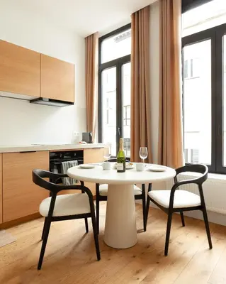 a white table and chairs in a room with a kitchen at Stylish 1BR Apartment near Zuid in Antwerp