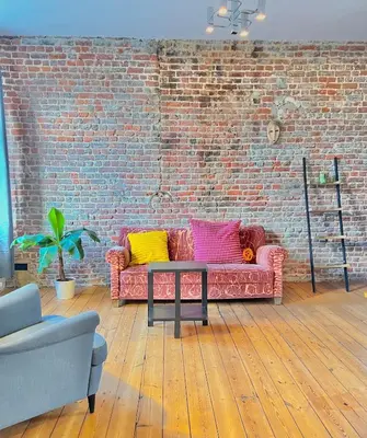 a living room with a pink couch and a brick wall at Big cosy Family Duplex near Grande Place in Brussels