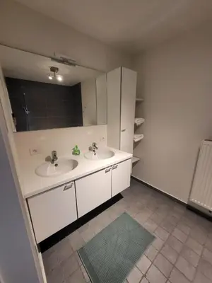 a white bathroom with two sinks and a mirror at Ruim appartement met terras in Ghent