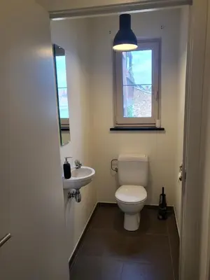 a bathroom with a toilet and a sink and a window at Ruim appartement met terras in Ghent