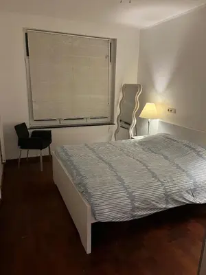 a bedroom with a bed and a window with a chair at A soothing nest in Brussels