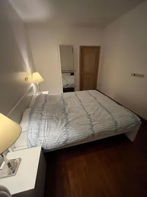 a small bedroom with a bed and a desk and lamp at A soothing nest in Brussels