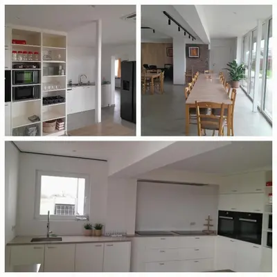 a kitchen and dining room with white cabinets and a table at Vakantiehuis 't Alkeveld in Zottegem