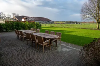 a wooden table and chairs with a field in the background at Vakantiehuis 't Alkeveld in Zottegem