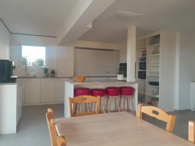 a kitchen with a wooden table and red stools at Vakantiehuis 't Alkeveld in Zottegem