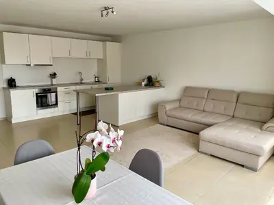 a kitchen and living room with a table and a couch at Bright & Peaceful Appartment in Koningslo in Vilvoorde