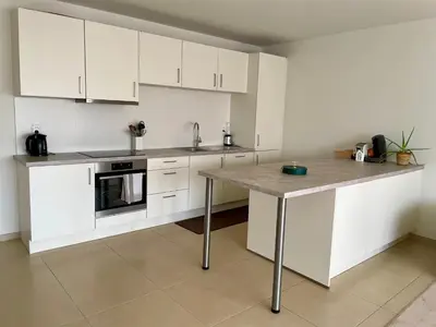 a kitchen with white cabinets and a table in it at Bright & Peaceful Appartment in Koningslo in Vilvoorde