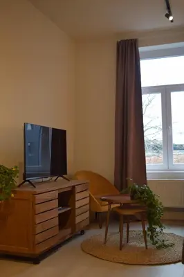 a living room with a television on a wooden dresser at Holiday Home La Petite Maison in Ghent