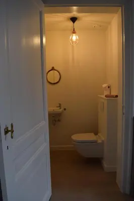 a bathroom with a toilet and a sink and a light at Holiday Home La Petite Maison in Ghent