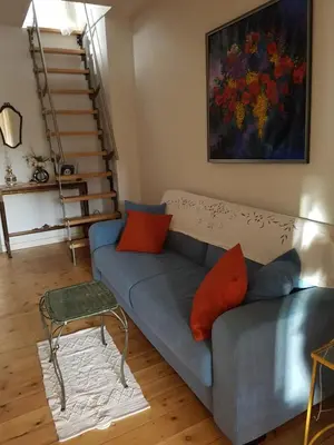 a living room with a blue couch with orange pillows at Guest House Dasos Kynthos in Brussels
