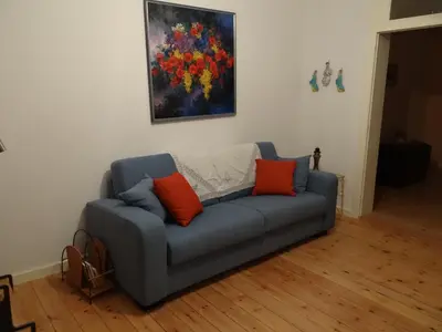 a blue couch with two orange pillows in a living room at Guest House Dasos Kynthos in Brussels