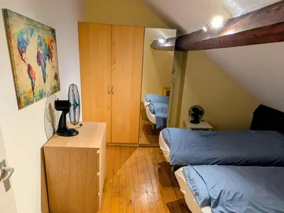 a attic bedroom with two beds and a cabinet at Duplex 3BR apartment near supermarkets & metro in Brussels