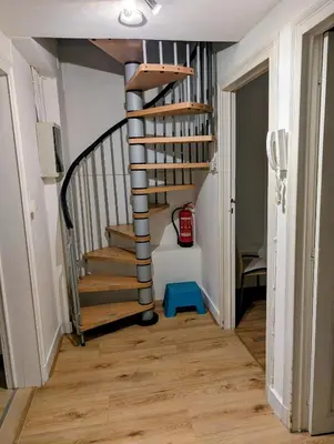 a spiral staircase in a house with a blue stool at Duplex 3BR apartment near supermarkets & metro in Brussels
