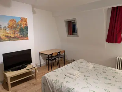 a bedroom with a bed and a table with a television at Duplex 3BR apartment near supermarkets & metro in Brussels