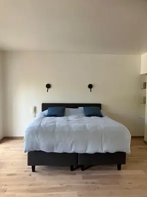a bedroom with a large white bed with blue pillows at RS10 One-Bedroom Apartment in Turnhout