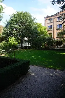 a park with a tree in front of a building at Stylish apartment in 16th century city palace! in Antwerp