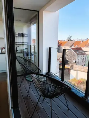 a balcony with two chairs and a large window at La Petite Foret Stylish City Apartment Ghent in Ghent