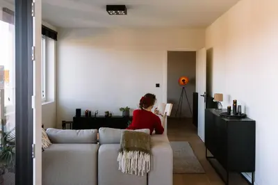 a woman sitting on a couch in a living room at La Petite Foret Stylish City Apartment Ghent in Ghent
