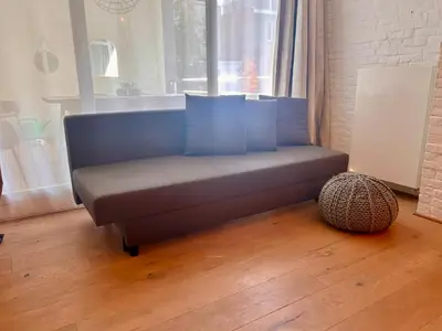 a blue couch sitting in a room with a window at The Vintage Warehouse Room in Antwerp
