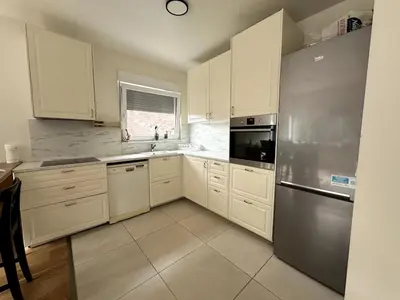 a kitchen with white cabinets and a stainless steel refrigerator at Cozy&Spacious apartment with garden in Antwerp