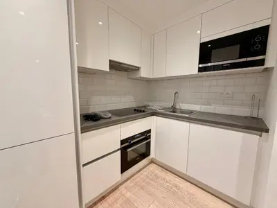 a white kitchen with white cabinets and a sink at Louise in Mellet