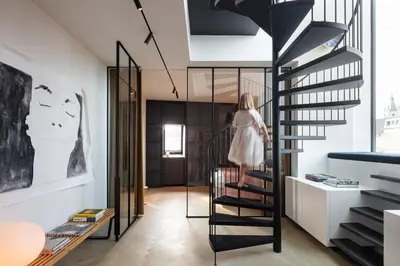 a woman walking down a spiral staircase in a room at Design penthouse800Y of history in one glimpse in Ghent