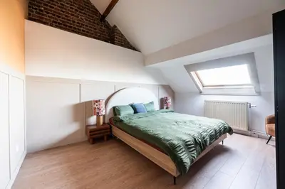 a bedroom with a bed with a green comforter and a window at Spacious 5-room house near Brussels with private parking in Steenokkerzeel