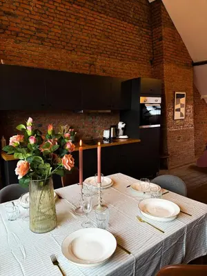 a table with plates and candles and a vase with flowers at NEW Luna residences - in the city center in Antwerp