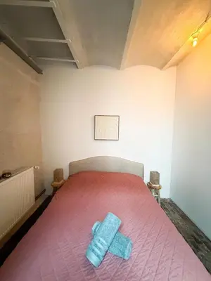 a bedroom with a pink bed with two blue sheets at NEW Luna residences - in the city center in Antwerp