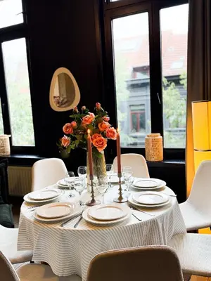 a table with plates and a vase of flowers on it at NEW Luna residences - in the city center in Antwerp