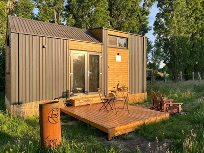 a small cabin with a deck and a table and chairs at Liberty Lodge X by Tiny Away in Kalmthout