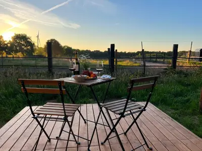 a table with two chairs and a glass of wine at Liberty Lodge X by Tiny Away in Kalmthout