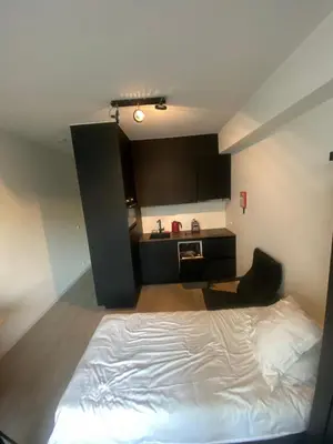 a bedroom with a white bed and a kitchen at Cosy Apartment in Antwerp in Antwerp