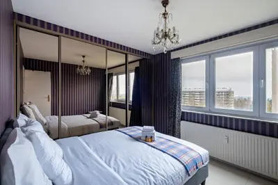 a bedroom with two beds and a chandelier and windows at Brussels Expo Elegant residence in Brussels