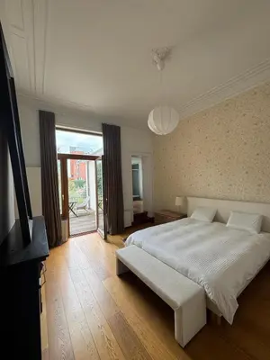 a bedroom with a white bed and a large window at Un paradis au coeur de Bruxelles in Brussels