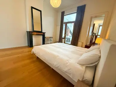 a bedroom with a large white bed and a mirror at Un paradis au coeur de Bruxelles in Brussels