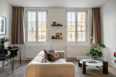a living room with a couch and two windows at A Place Antwerp - Boutique Suites & Flats - Vrijdagmarkt 18 in Antwerp